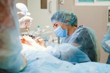 A doctor wearing a surgery hat performs surgery.