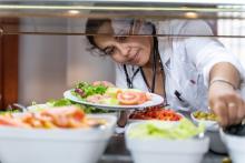 A health worker stocks up for lunch at a hospital canteen. She is eating salad-type food.