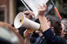 A person holding a sign and talking through a megaphone.