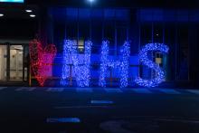 NHS in bright blue lights in the evening.