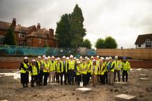 A group of people with hard hats and reflective jackets, standing on a building site.