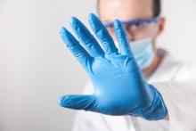 Doctor with blue gloves using the stop signal.