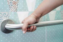 A hand holding a rail in a bathroom