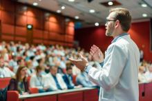A doctor delivers a speech to a room of medical professionals.