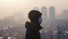 Person wearing mask in front of polluted city