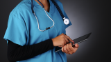 A doctor in scrubs with a stethescope and a tablet device