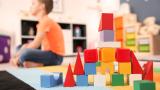 A tower of block toys in the centre of the image, a little boy is in the background out of focus.