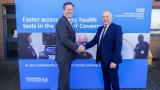 An image of two men shaking hands in front an NHS Coventry sign.