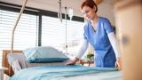 A nurse makes a hospital bed.