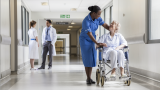 A hospital corridor, with hospital staff and a patient in a wheelchair