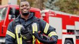 Firefighter smiling in front of a fire engine.