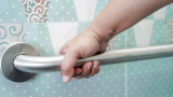 A hand holding a rail in a bathroom