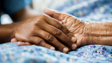 A nurse and a patient holding hands