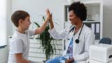 Child hi fives female doctor