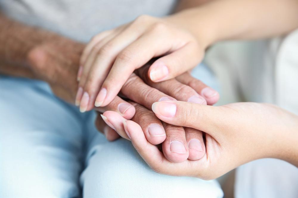 Two people holding hands in a comforting way.