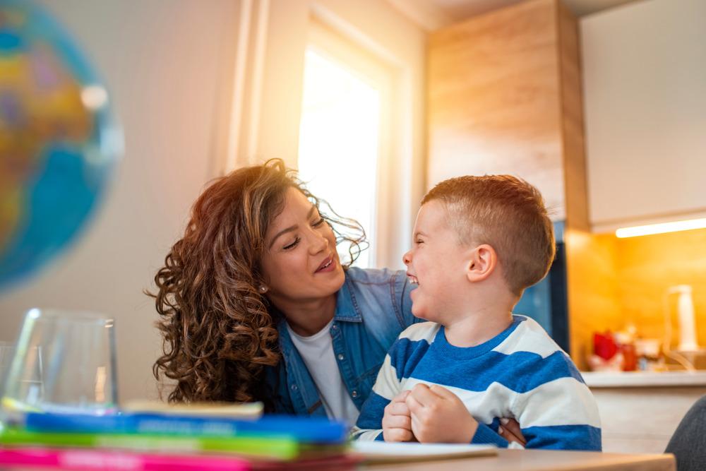 A little boy laughing with a tutor of some sort.