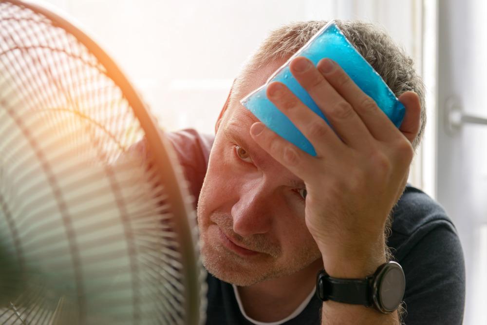 A very hot man in front of a fan.