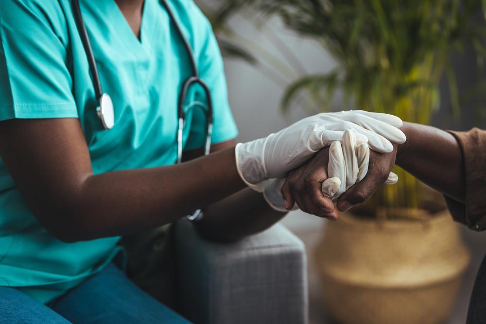 Healthcare worker holding hands with a patient in a caring way.