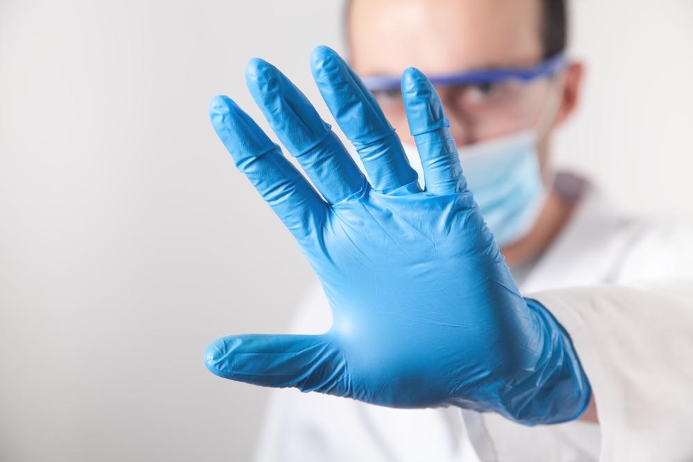 Doctor with blue gloves using the stop signal.